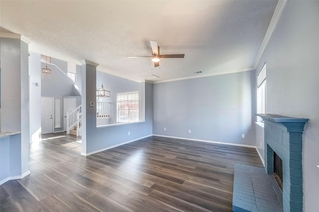 unfurnished living room featuring ceiling fan, dark wood-type flooring, a textured ceiling, a fireplace, and ornamental molding