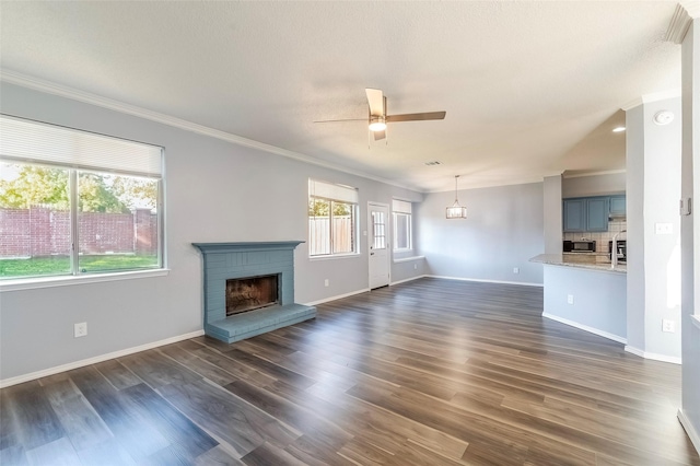 unfurnished living room with ceiling fan, dark hardwood / wood-style floors, crown molding, and a brick fireplace