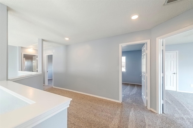 hall featuring carpet and a textured ceiling