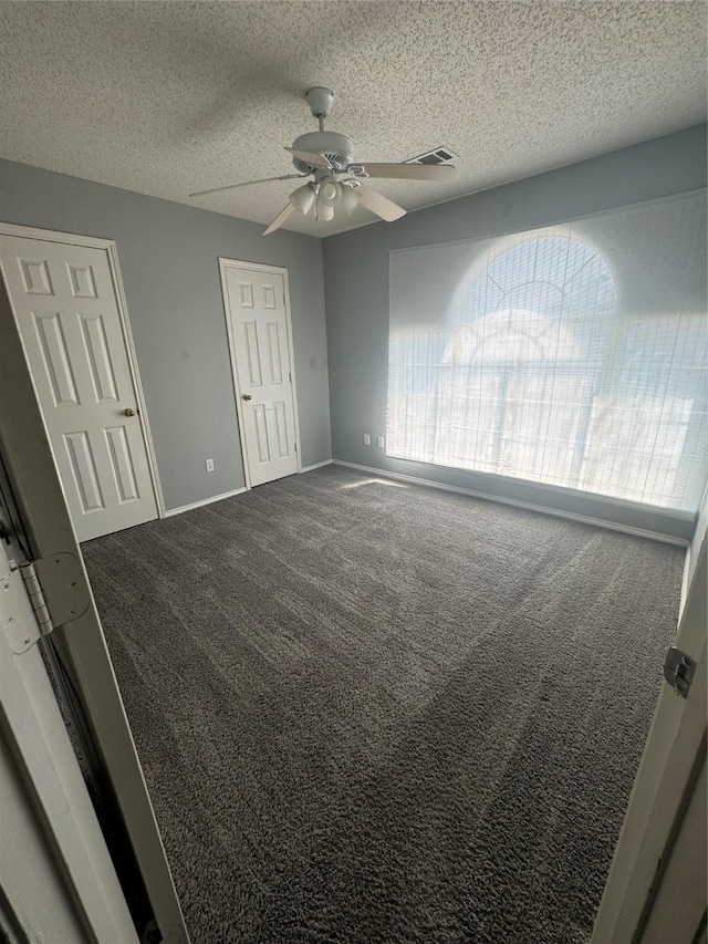 unfurnished bedroom featuring carpet, ceiling fan, and a textured ceiling