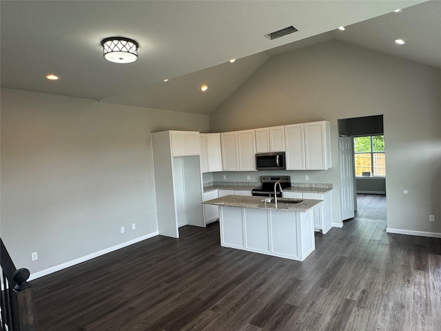 kitchen with white cabinets, light stone counters, stainless steel appliances, dark wood-type flooring, and a center island with sink