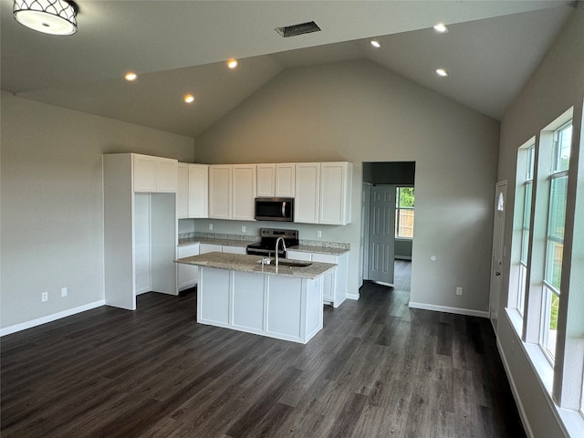 kitchen featuring white cabinets, high vaulted ceiling, dark wood-type flooring, appliances with stainless steel finishes, and a kitchen island with sink