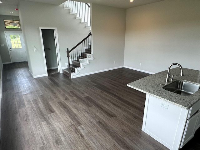 kitchen with dark hardwood / wood-style floors, a towering ceiling, sink, white cabinets, and light stone counters