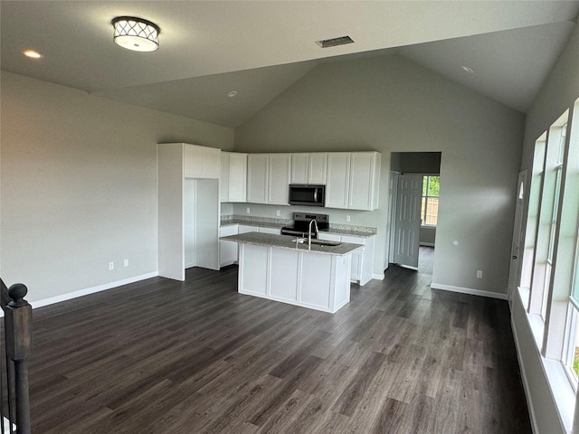 kitchen featuring sink, dark wood-type flooring, light stone countertops, an island with sink, and white cabinets