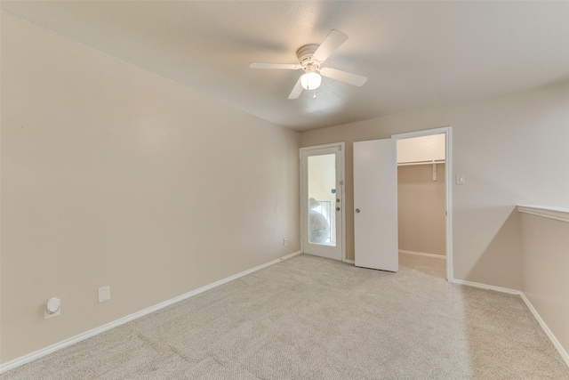 unfurnished bedroom featuring a spacious closet, light carpet, ceiling fan, and a closet