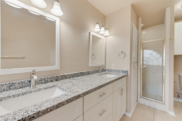 bathroom with a shower with shower door, tile patterned floors, double sink vanity, and toilet