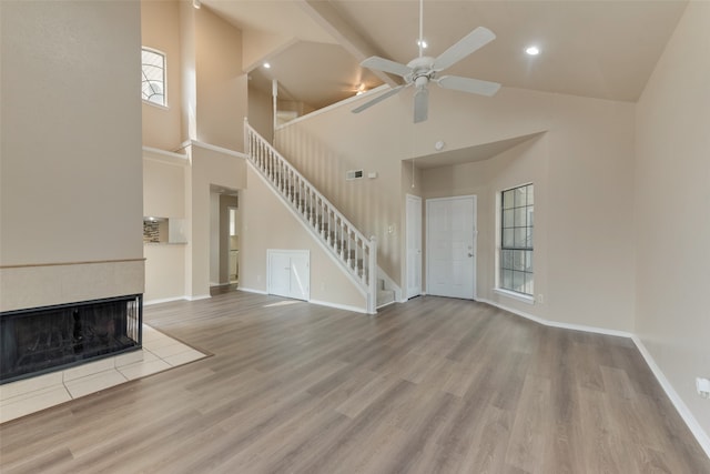 unfurnished living room featuring high vaulted ceiling, light wood-type flooring, and ceiling fan