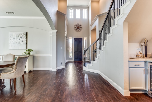 entrance foyer featuring hardwood / wood-style floors, a towering ceiling, and ornamental molding