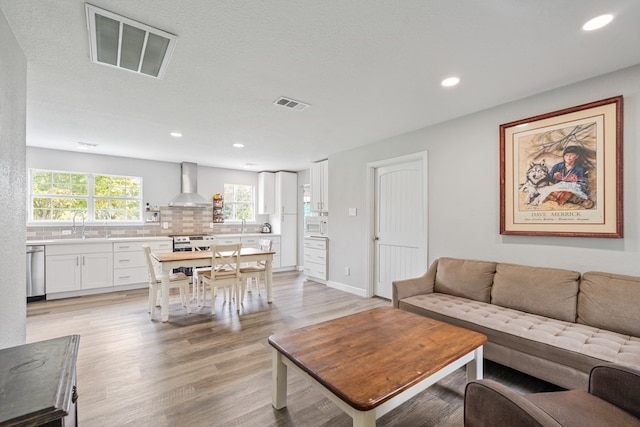 living room featuring light wood-type flooring, visible vents, baseboards, and recessed lighting