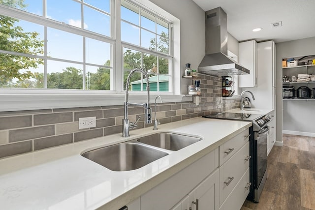 kitchen with dark wood-type flooring, white cabinets, range with electric cooktop, and wall chimney exhaust hood