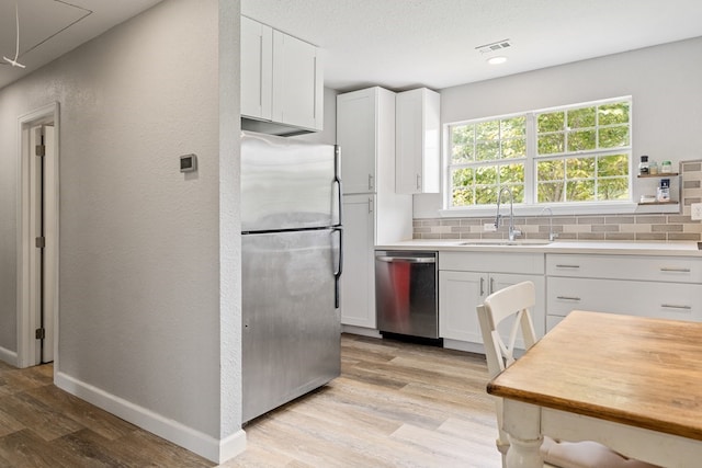 kitchen featuring appliances with stainless steel finishes, light wood-type flooring, decorative backsplash, and sink