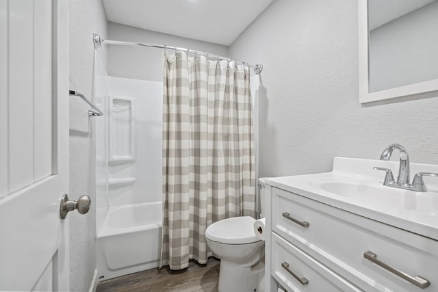 bathroom featuring a textured wall, toilet, wood finished floors, shower / bathtub combination with curtain, and vanity
