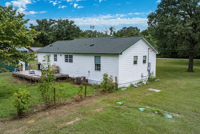 rear view of house featuring a shingled roof, a lawn, a deck, and central air condition unit