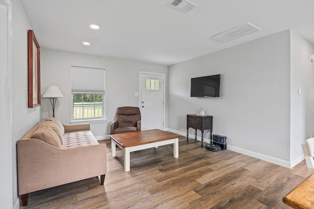 living room featuring baseboards, visible vents, wood finished floors, and recessed lighting