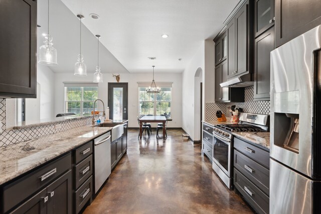 kitchen with stainless steel appliances, hanging light fixtures, decorative backsplash, sink, and light stone counters