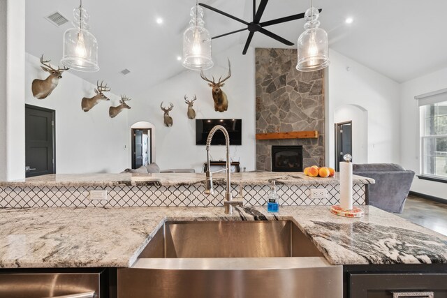 kitchen featuring a fireplace, hanging light fixtures, and lofted ceiling