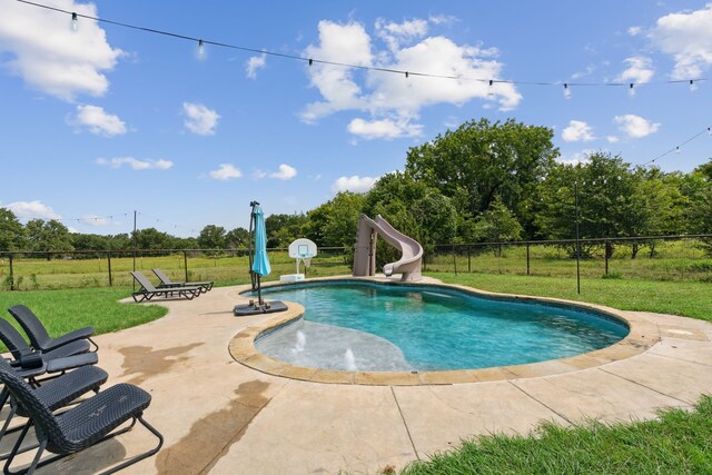 view of swimming pool with a water slide, a yard, and a patio area