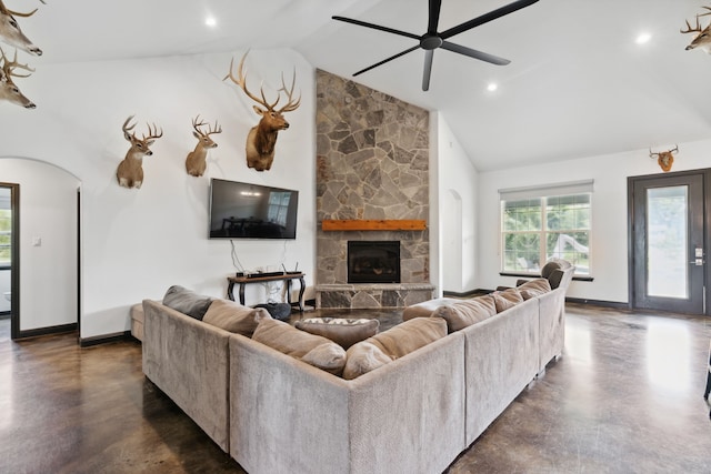 living room featuring a stone fireplace, high vaulted ceiling, and ceiling fan