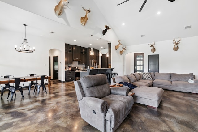 living room featuring high vaulted ceiling, sink, and ceiling fan with notable chandelier