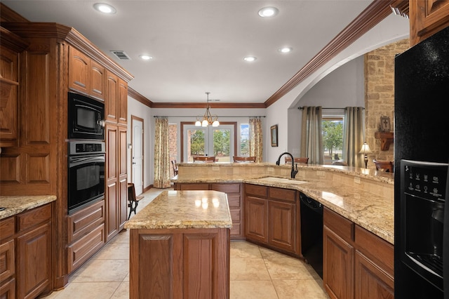 kitchen with a sink, ornamental molding, black appliances, brown cabinetry, and pendant lighting