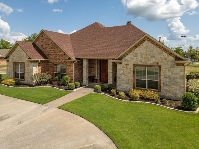 view of front of home with a front lawn, a chimney, a shingled roof, and brick siding