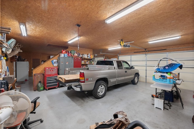 garage with a garage door opener and freestanding refrigerator