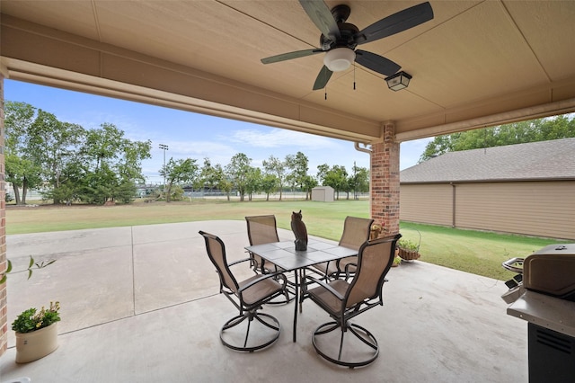 view of patio / terrace featuring an outbuilding, ceiling fan, a grill, a storage unit, and outdoor dining space