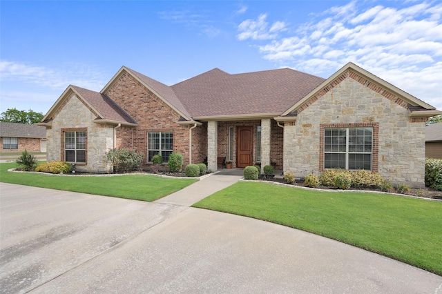 view of front of home with a shingled roof, brick siding, and a front lawn