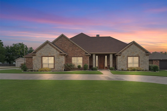 view of front of property featuring a yard, brick siding, a chimney, and roof with shingles