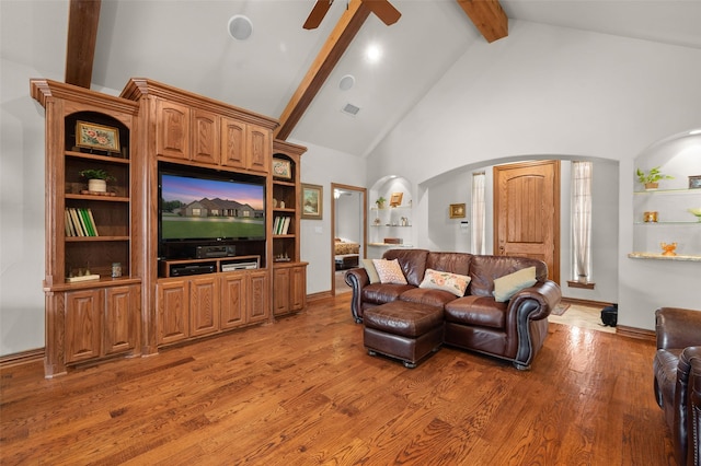 living area featuring arched walkways, beam ceiling, a ceiling fan, high vaulted ceiling, and light wood-type flooring