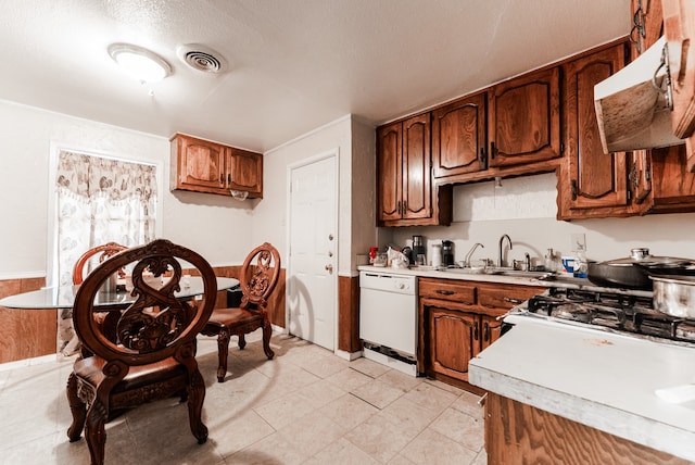 kitchen with light tile patterned floors, a textured ceiling, premium range hood, white dishwasher, and sink