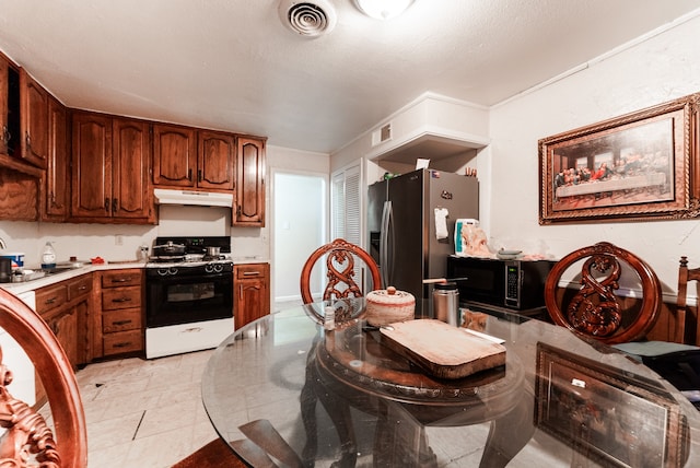 kitchen featuring black microwave, range with electric cooktop, stainless steel fridge, sink, and light tile patterned floors