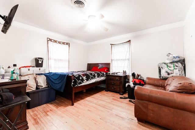 bedroom featuring ceiling fan, light wood-style floors, visible vents, and ornamental molding