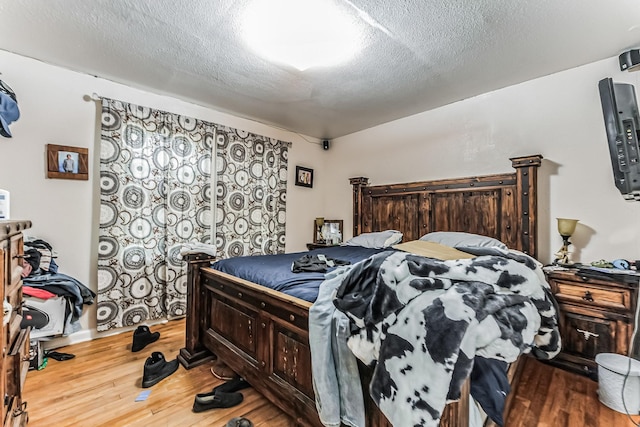 bedroom with a textured ceiling and wood finished floors