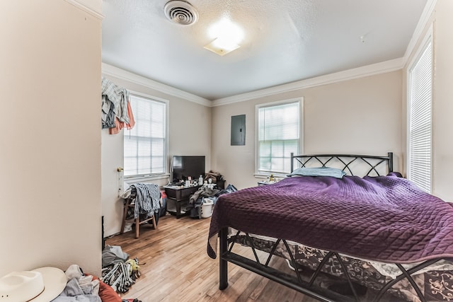 bedroom with crown molding, hardwood / wood-style floors, and electric panel