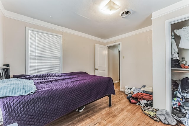 bedroom with visible vents, crown molding, and wood finished floors