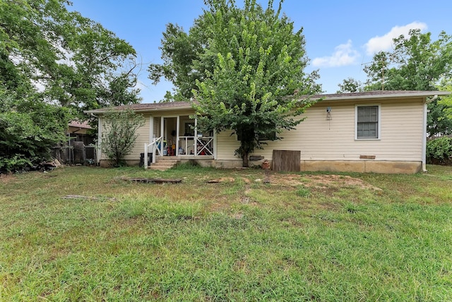 rear view of house featuring a lawn, covered porch, and fence