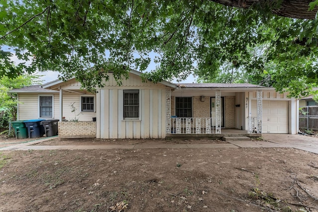 single story home with a porch, board and batten siding, concrete driveway, an attached garage, and brick siding