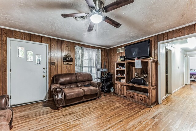 living area with visible vents, a textured ceiling, a ceiling fan, and light wood finished floors