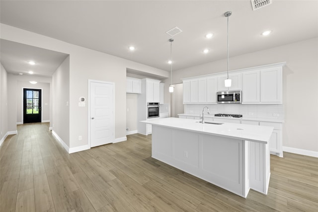 kitchen featuring sink, a kitchen island with sink, white cabinetry, stainless steel appliances, and light hardwood / wood-style floors