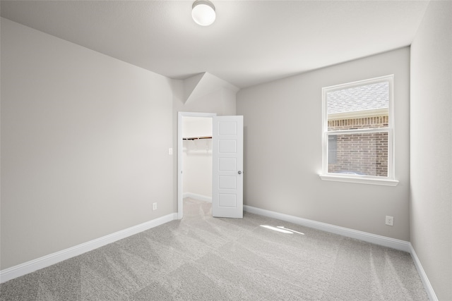 unfurnished bedroom featuring light carpet, a closet, and a walk in closet