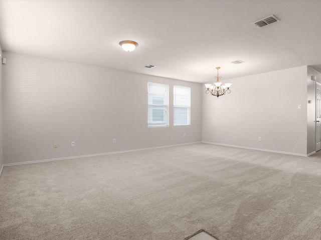 empty room featuring light colored carpet and a notable chandelier