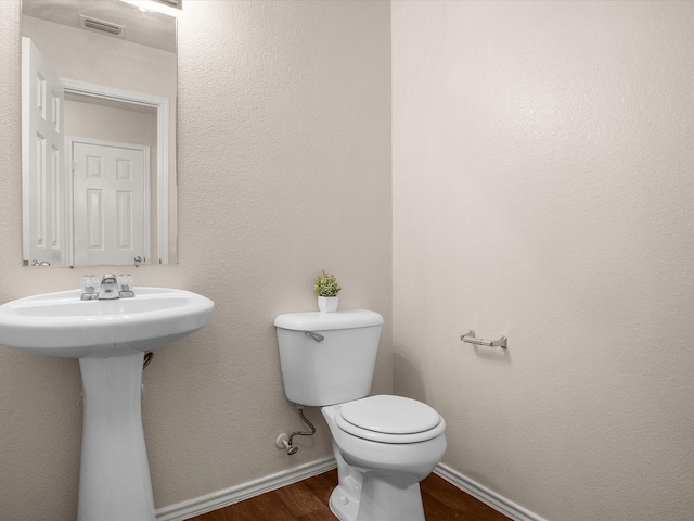 bathroom with hardwood / wood-style flooring and toilet