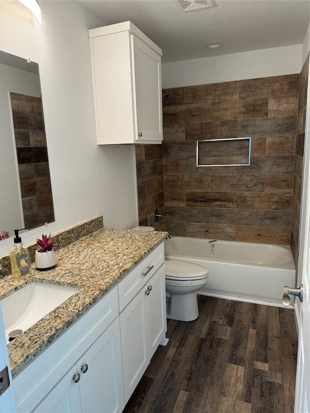 full bathroom with vanity, tiled shower / bath combo, wood-type flooring, and toilet