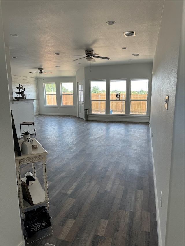 unfurnished living room featuring a textured ceiling, dark hardwood / wood-style flooring, and ceiling fan