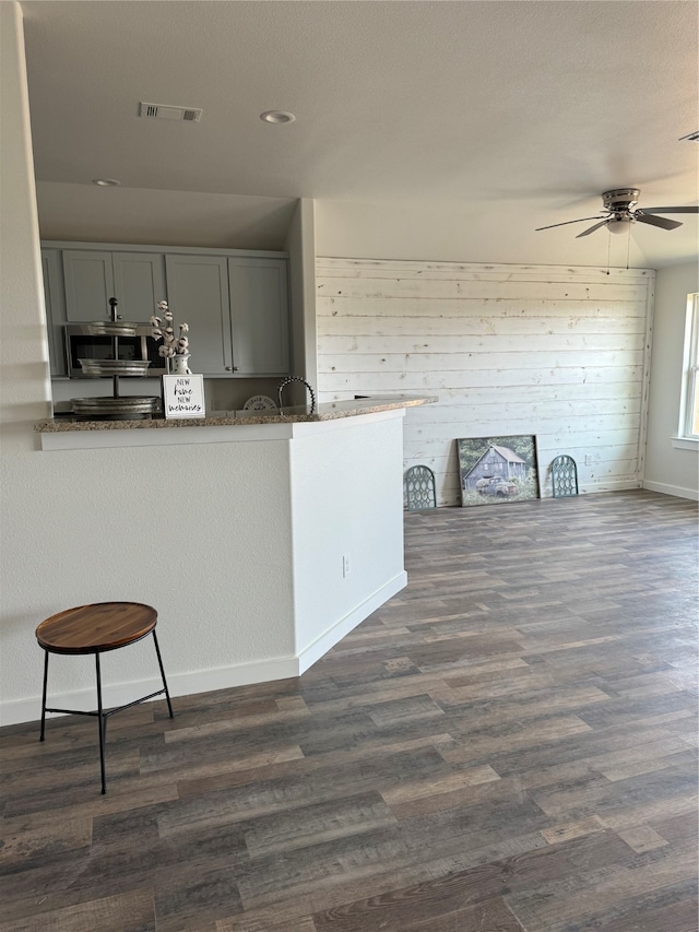 kitchen with wood walls, ceiling fan, gray cabinets, and hardwood / wood-style floors