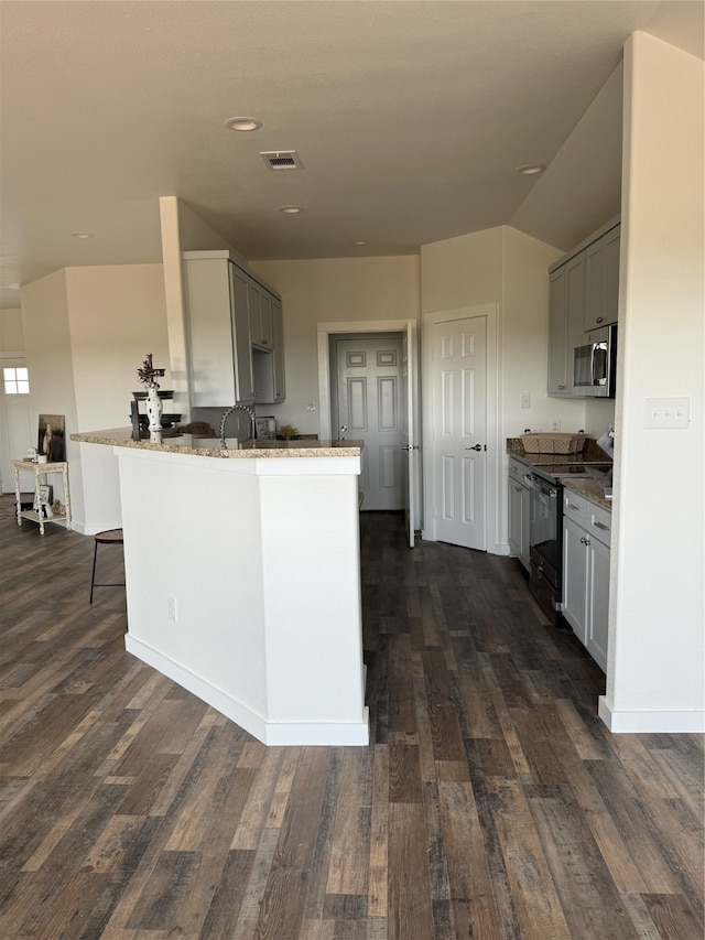 kitchen featuring stainless steel microwave, gray cabinets, dark hardwood / wood-style floors, range with electric cooktop, and stone countertops