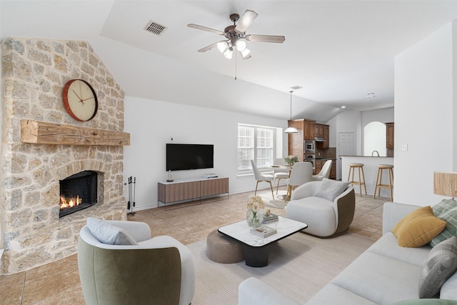 living room featuring ceiling fan, vaulted ceiling, light tile patterned flooring, and a fireplace