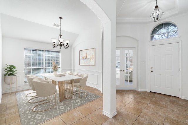 entryway with a chandelier, a raised ceiling, french doors, light tile patterned floors, and crown molding