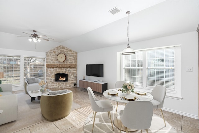 tiled dining space with ceiling fan, plenty of natural light, lofted ceiling, and a fireplace